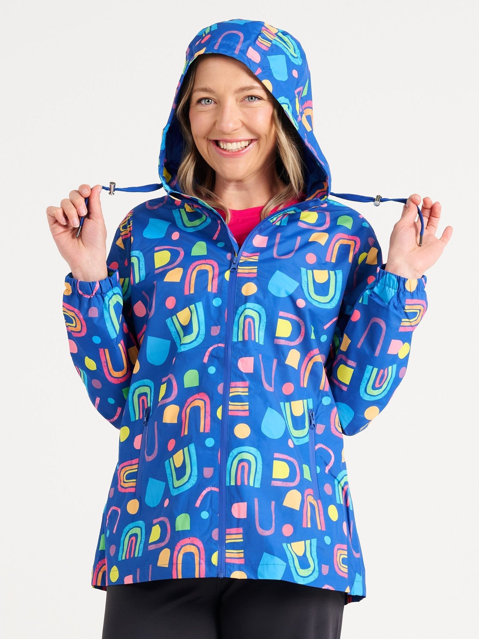 Jennifer wearing the Rainbow Warrior Raincoat in size S, colourful rainbow printed waterproof raincoat