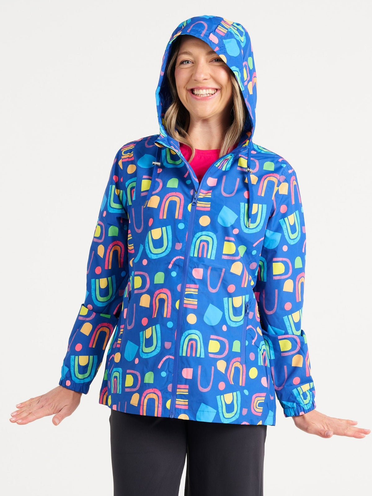 Jennifer wearing the Rainbow Warrior Raincoat in size S, colourful rainbow printed waterproof raincoat