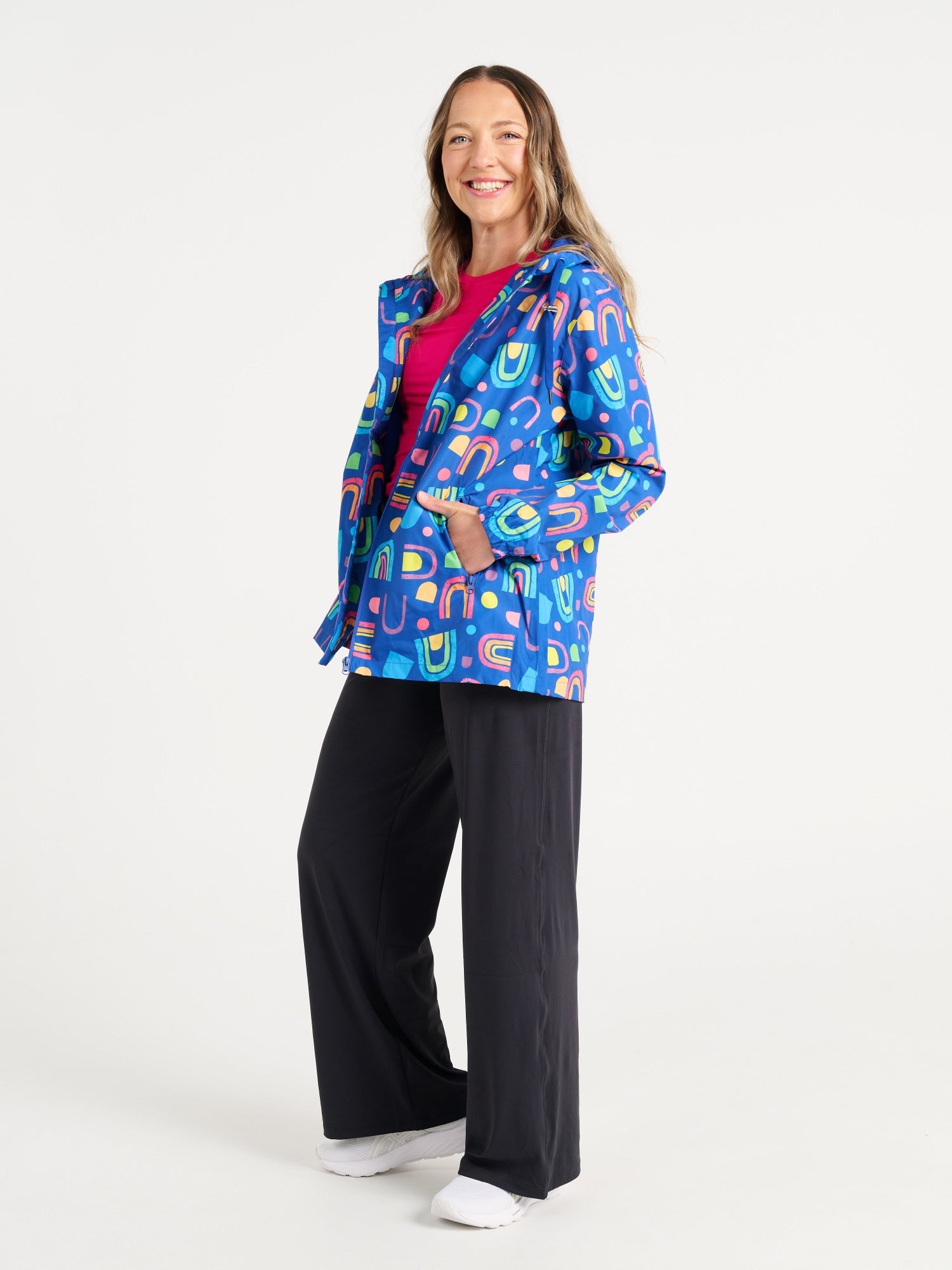 Jennifer wearing the Rainbow Warrior Raincoat in size S, colourful rainbow printed waterproof raincoat