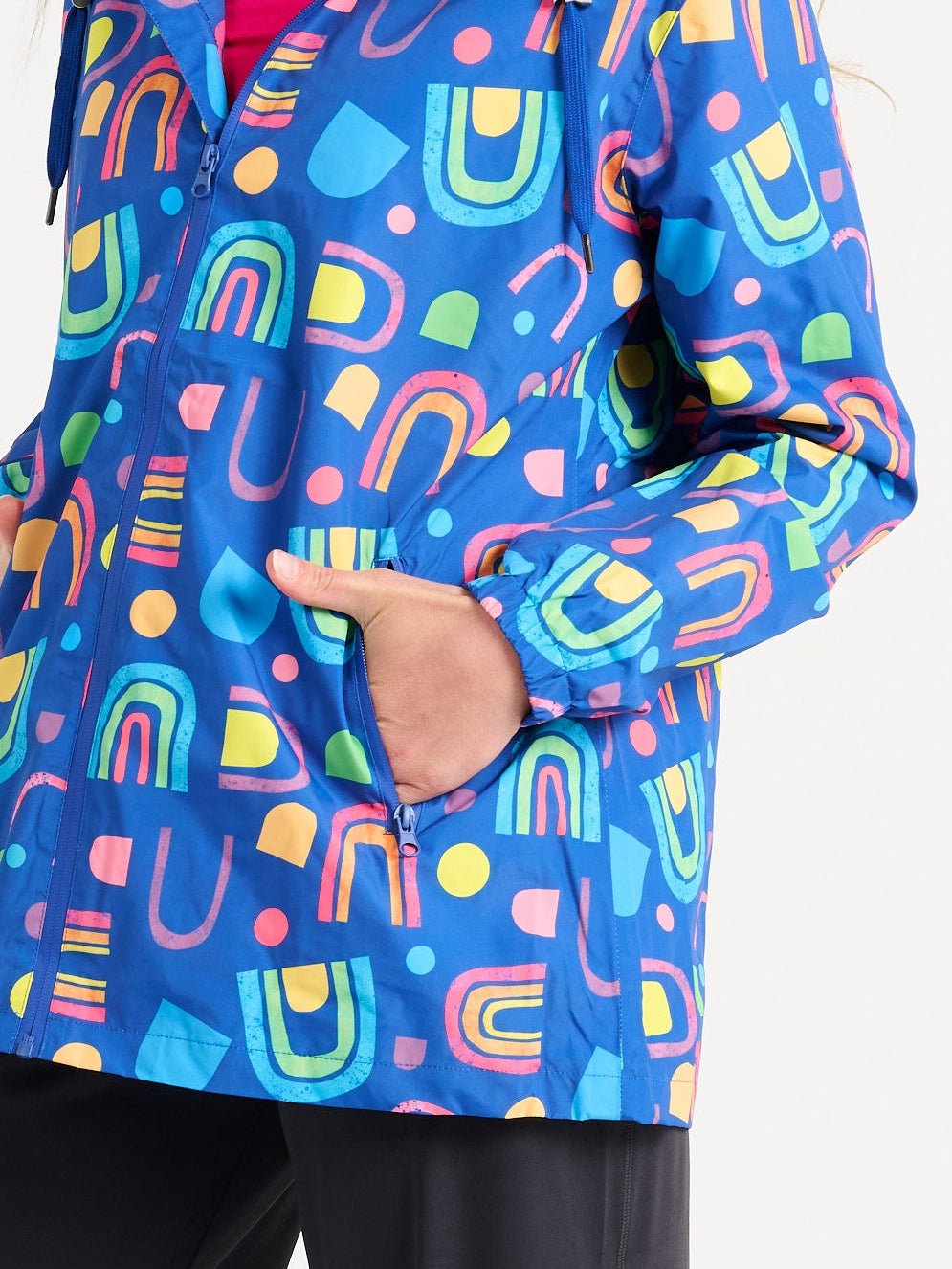 Jennifer wearing the Rainbow Warrior Raincoat in size S, colourful rainbow printed waterproof raincoat