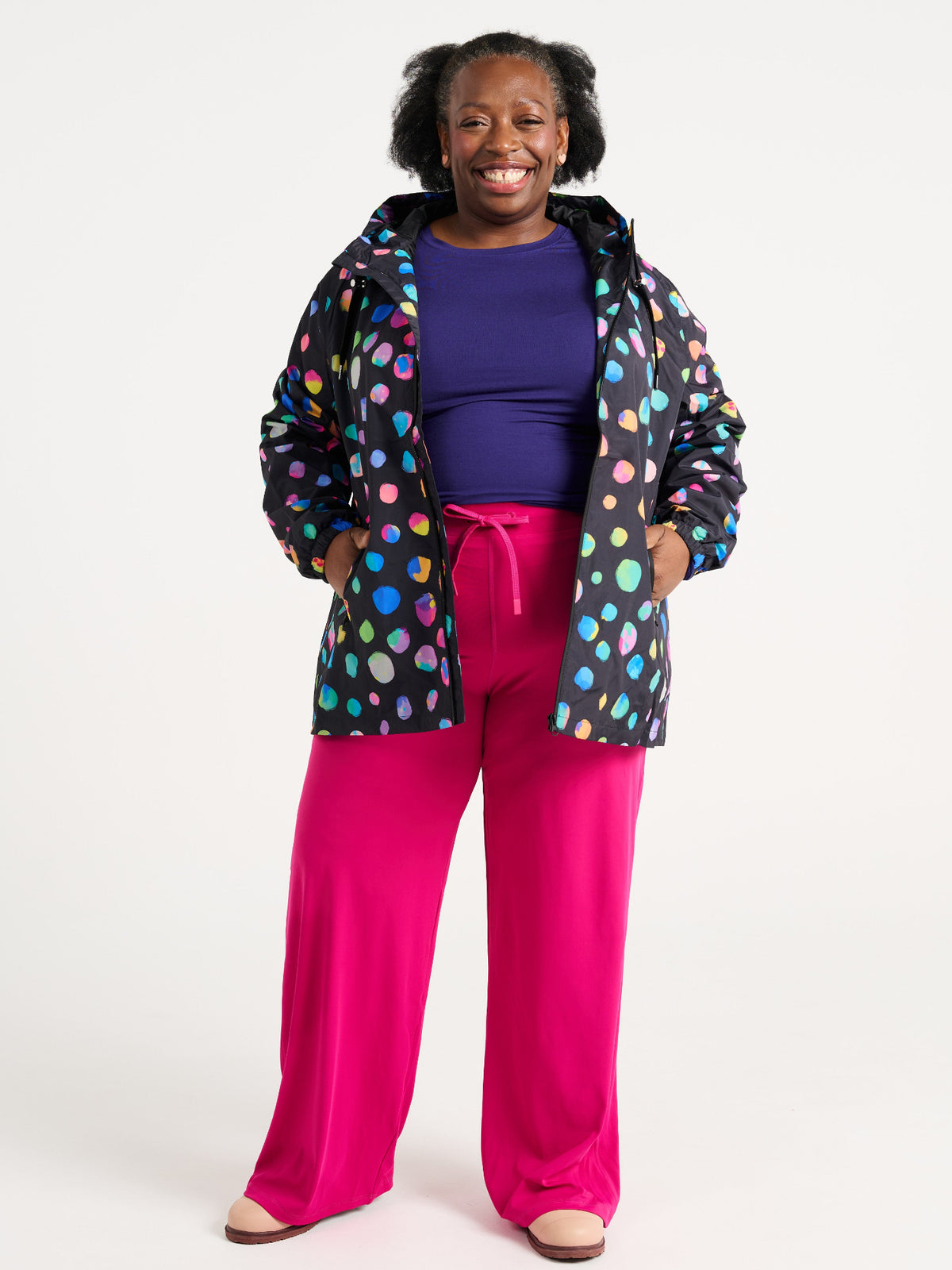 Zee wearing the Night Polka Raincoat in size 3XL, colourful rainbow spotted waterproof raincoat