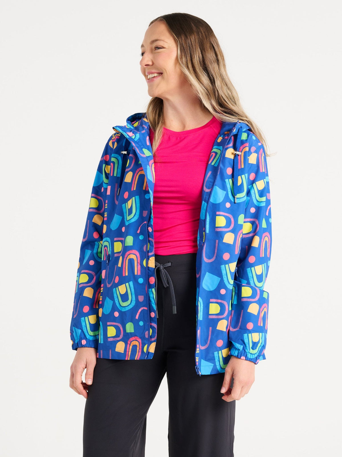 Jennifer wearing the Rainbow Warrior Raincoat in size S, colourful rainbow printed waterproof raincoat