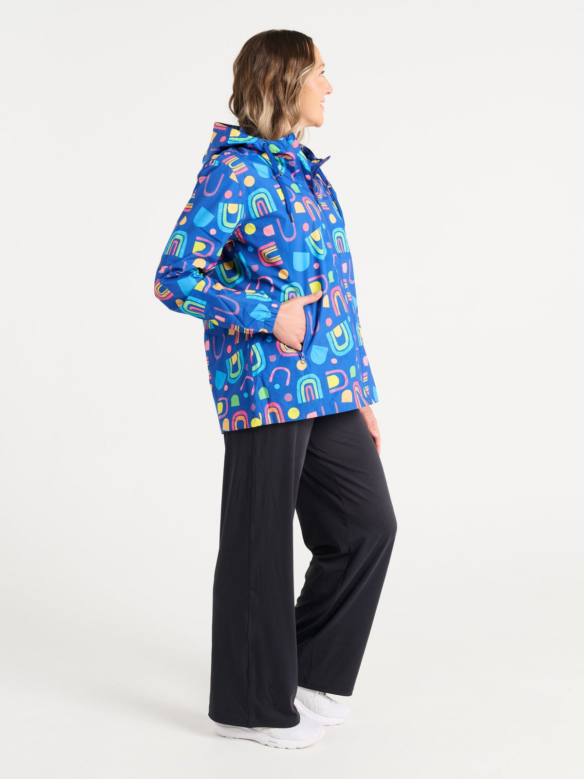 Jennifer wearing the Rainbow Warrior Raincoat in size S, colourful rainbow printed waterproof raincoat